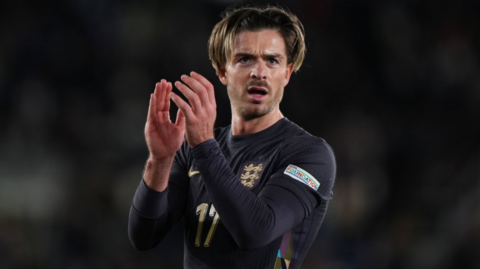 Jack Grealish applauds fans at the final whistle of England's away game against Finland