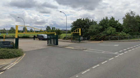 A Google streetview image showing the development land. Rugby posts are visible to the far left, while vegetation covers the land slated for development.