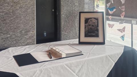 A black and white framed photograph of Kevin Keegan sits on a white tablecloth next to the open book of condolence at Newcastle Civic Centre.