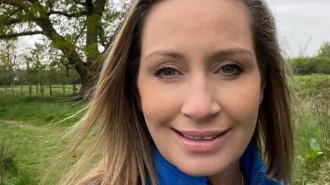 Close up of Nicola Bulley smiling at the camera with a field and trees in the background