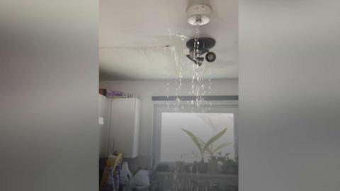 Water raining down from a light fixture into a kitchen