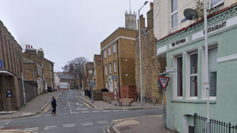 A cross roads with brick buildings lining the road. To the right there is a restaurant which is painted turquoise.