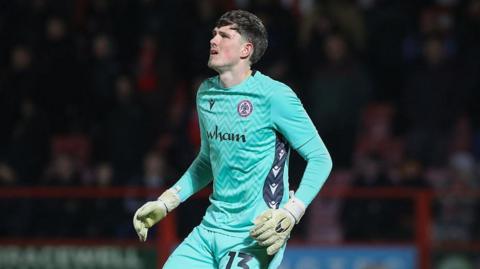 Ollie Wright on the pitch with his arms by his side, wearing Accrington kit, during a match