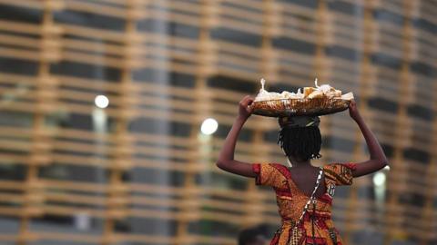 A woman carries a basket on her head