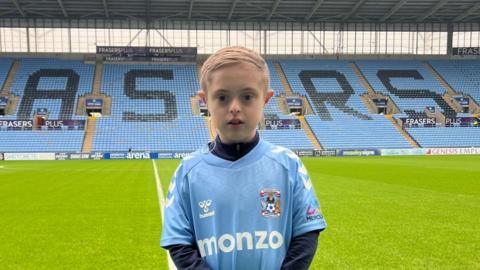 Archie, wearing a Coventry City kit by the side of the pitch at the CBS Arena in Coventry