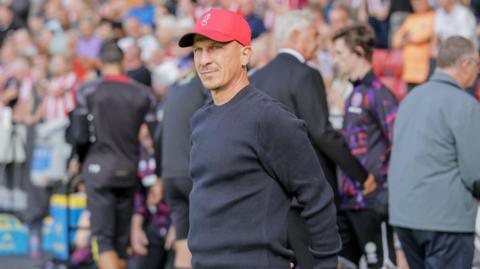 Gerhard Struber standing with his hands behind his back in the dugout 