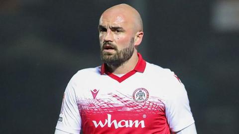 Farrend Rawson in the red and white shirt of Accrington Stanley