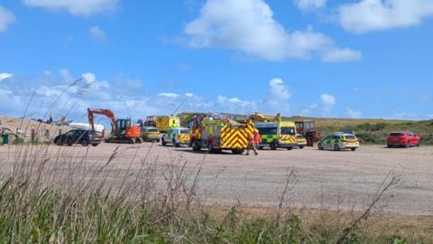 Emergency service vehicles, including ambulances and fire engines, in a car park at Weybourne Beach in Sheringham.