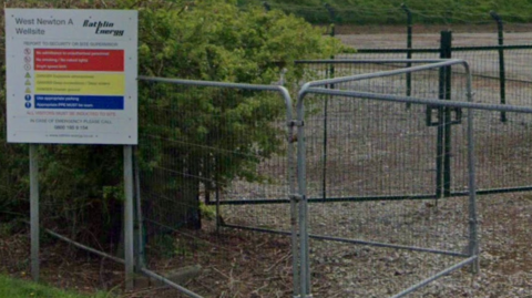 Google view of a sign next to a perimeter fence. The sign bears the name Rathlin Energy, along with a reference to West Newton. There are also details of site information, including warnings about uneven ground and deep excavations.