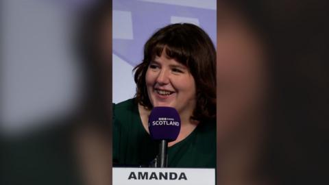 Amanda speaking into a BBC Radio Scotland microphone and smiling