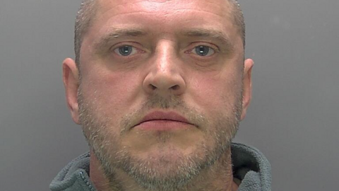 Paul Page is looking at the camera in a police custody photo. He is balding and has a stubbly beard and moustache.