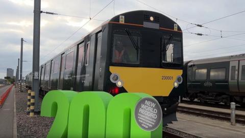A black and yellow GWR train sitting at a platform with large green 200 sign