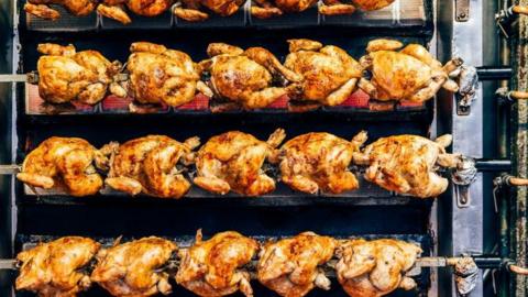 A row of cooked rotisserie chickens 