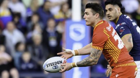Zac Lipowicz throws a pass wearing a red Catalans Dragons kit