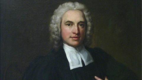 A painted portrait of Charles Wesley. He has grey curly hair and is wearing a black robe with a white cravat around his neck.