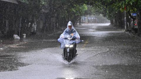 A motorbike rider wades through a partly flooded street during heavy rain in Vinh city, Nghe An province.