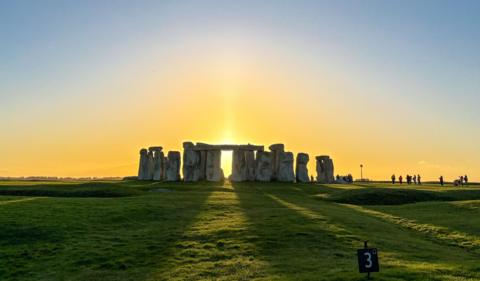 a low Sun peaks between the pillars of Stonehenge