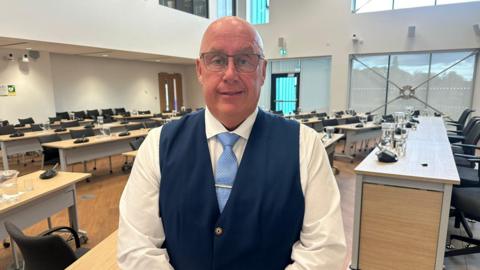 A man in a waistcoat and shirt wearing glasses