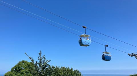 Two cable cars hanging against a bright blue sky