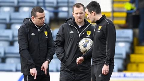 Match officials debate during a second pitch inspection at Dens Park