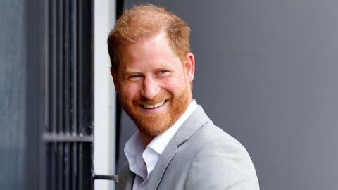 Prince Harry smiles in grey suit