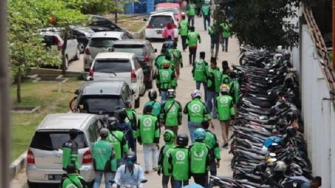 The motorcycle taxi drivers walking towards the hospital