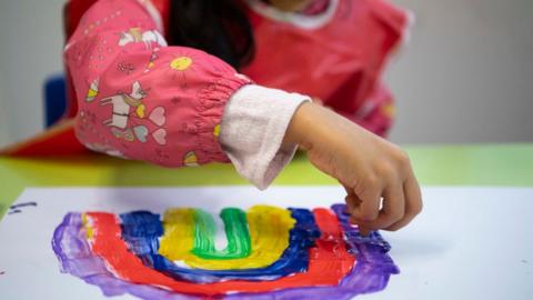 Child painting a rainbow in a school in London