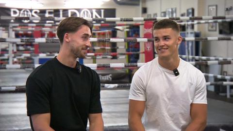 Owen (left) and Taylor Bevan pose for a photo with a boxing ring behind them