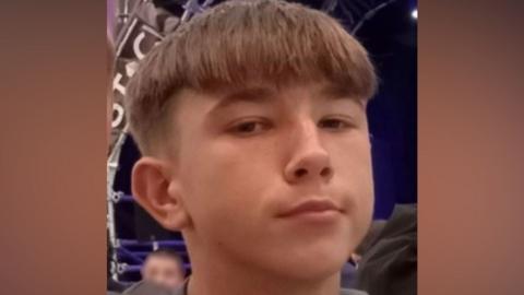 A teenager with short brown hair looks at the camera.