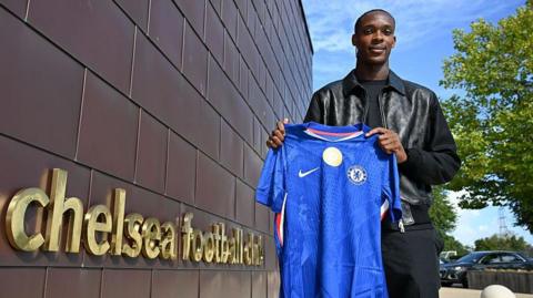 Emanuel Emegha holding a Chelsea home shirt