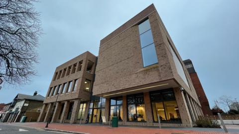 Thurrock Council building - a tall square block with long windows and a view through the offices on the ground floor