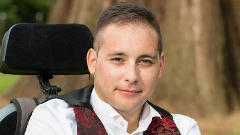 Karl Lee wearing a white shirt and red, printed waistcoat.