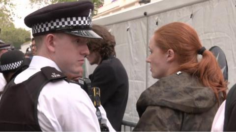 Alice Chambers standing handcuffed next to police officers