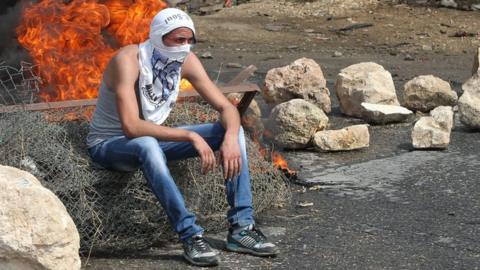 A Palestinian student from Palestine Polytechnic University sits during a protest against Israel near the Jewish settlement of Beit Hagai, October 2015