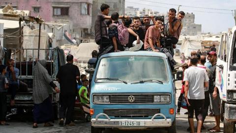 Palestinian men ride atop a van used for public transportation in Gaza City on August 8, 2025