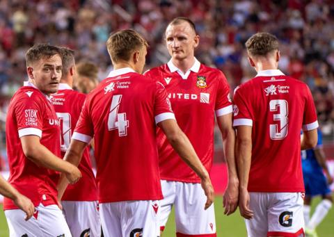 Wrexham players celebrate a goal against Chelsea during pre-season