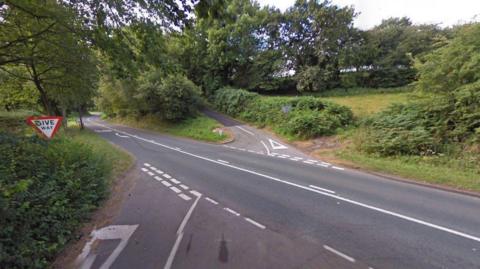 A Google street view image of a crossroads on a main road in a rural area. 
