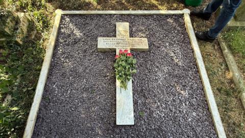 The grave of the first Titanic survivor, his and child. With a white marble cross and purple ceramic bits. 