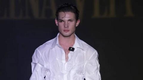 Clavicular in a white shirt on a runway. He has dark hair.