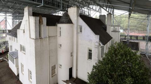 A large white building, with a protective roof and covering placed over the whole building