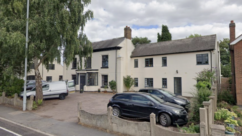 A white painted old building with cars infront