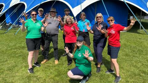 Nine people, the organisers of the festival, posing on grass outside a marquee