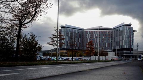 Queen Elizabeth University Hospital with dark clouds above