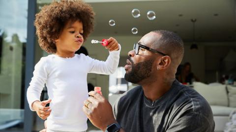 Ugo Monye helps his son blow bubbles in the garden.