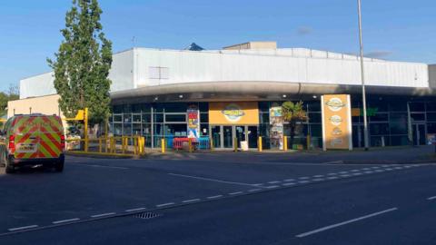 The front of Waterworld leisure attraction viewed from the main road. A police vehicle is parked on the entrance road. 