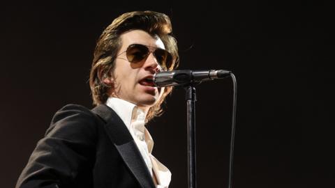 Arctic Monkeys frontman Alex Turner performing on stage