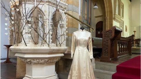 A wedding dress on a mannequin by a decorated pulpit