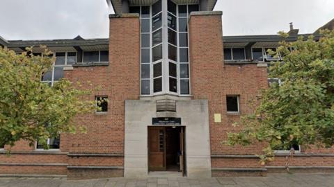 Isle of Wight Crown Court is a brick building with a stone-framed main entrance beneath a large window.