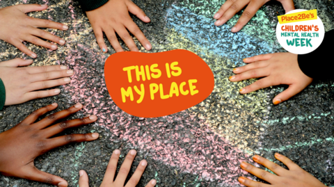 Children's hands can be seen placed on a chalk drawing in a children's playground.