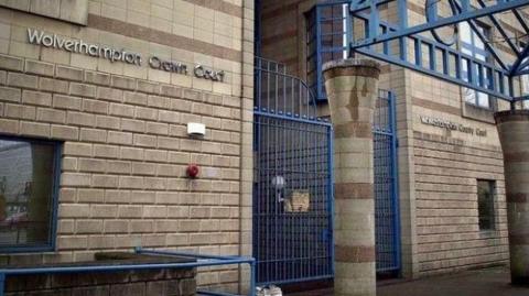 A brick building with a blue gate. Lettering on the wall reads "Wolverhampton Crown Court".